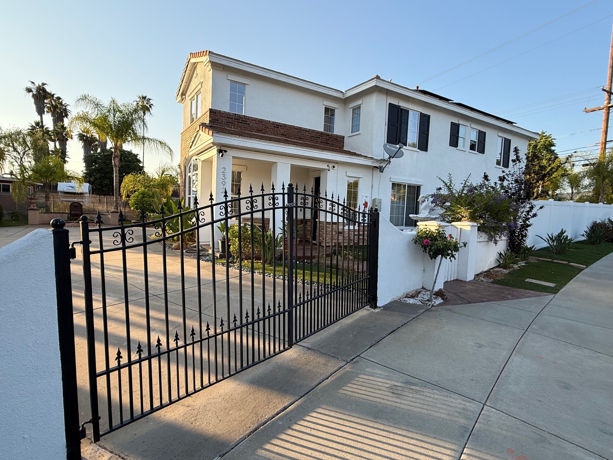 Front of a 2-story white house with a black iron gate